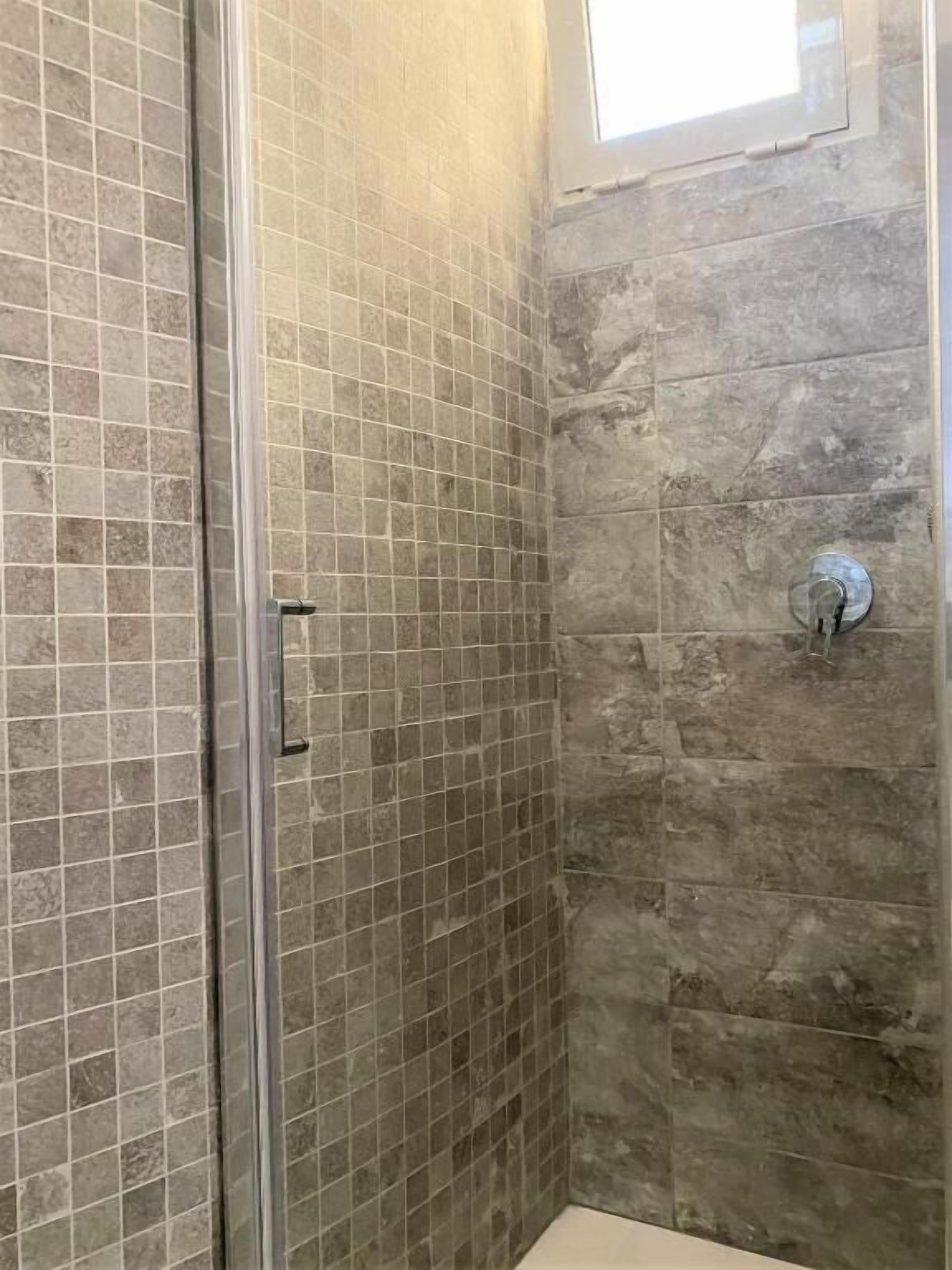 A shower area with tiled walls and a glass door.