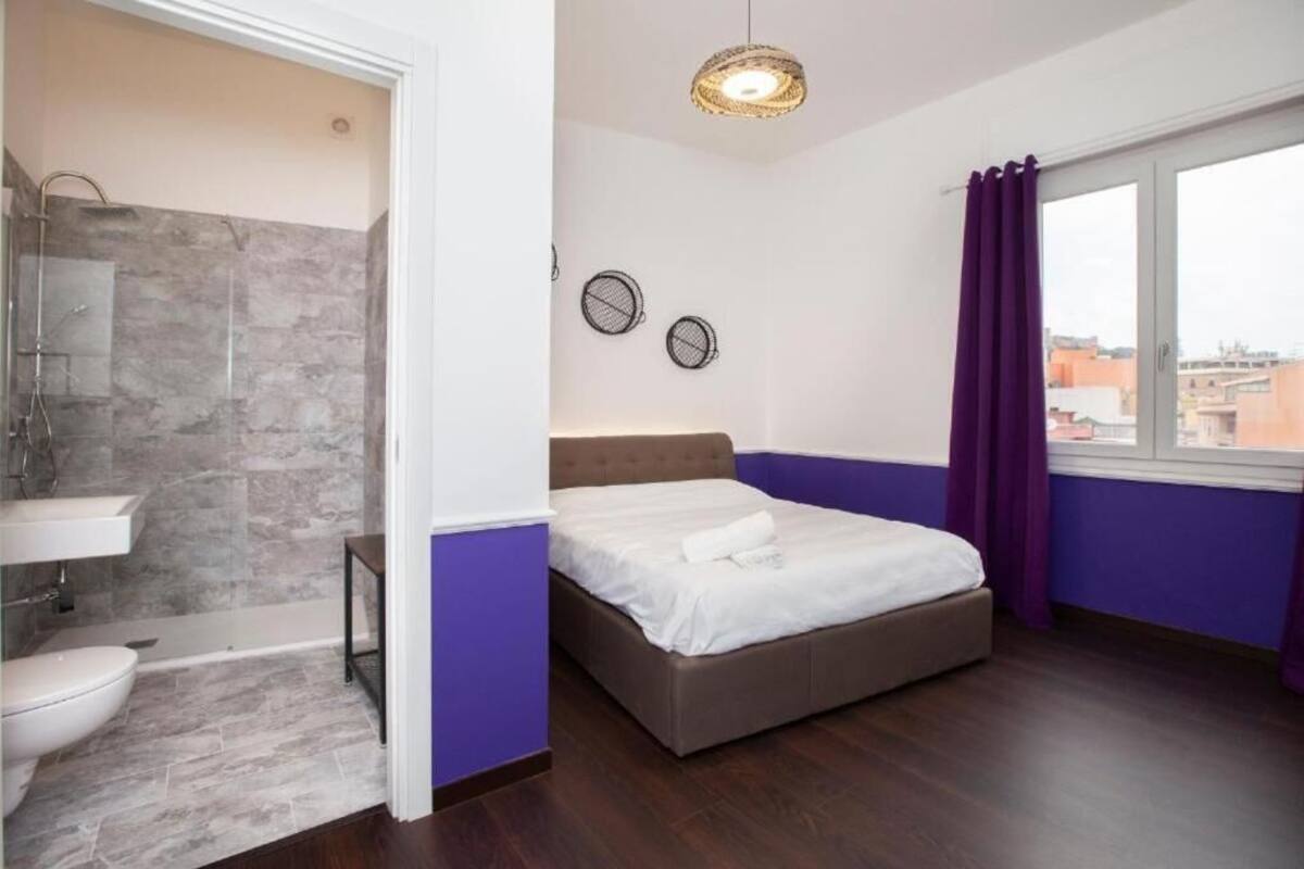 A bedroom with a bed, a window, a bathroom with a shower, and a sink.