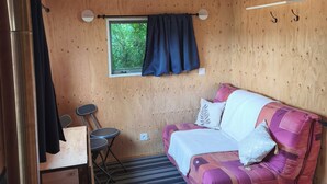 Een kamer met houten lambrisering, een bank, een tafeltje en een raam met gordijnen.