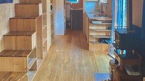 Een houten interieur met een trap, een keukenhoek en een open haard.