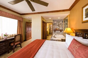 A hotel room with a bed, a desk, a chair, a bathroom with a bathtub, and a stone wall. - Park City Canyons, Large 4BR Villa, Private hot tub, Ski In/Out, Feb7-Feb14 '27 (Park City)