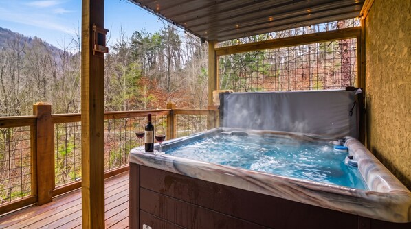 Un jacuzzi en una terraza de madera con vistas a un área boscosa.