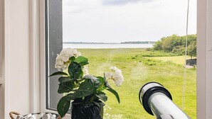Een raam met een telescoop, een pot met witte bloemen en een schaal met stenen.