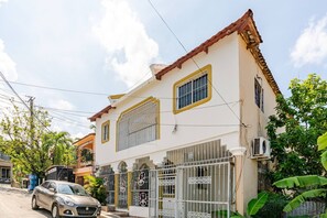 A two-story house with a gated entrance, a car parked in front, and a clear sky. - Una Estancia Moderna y Confortable (Puerto Plata)