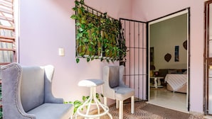 A room with two grey armchairs, a white stool, a potted plant, and a metal gate leading to another room. - Una Estancia Moderna y Confortable (Puerto Plata)