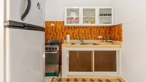 A compact kitchen with a refrigerator, stove, oven, and a cabinet with dishes. - Una Estancia Moderna y Confortable (Puerto Plata)