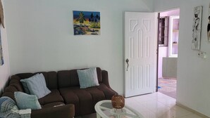 A living room with a brown sofa, a glass coffee table, and a painting on the wall. - Una Estancia Moderna y Confortable (Puerto Plata)