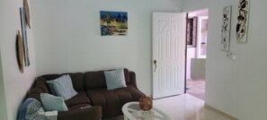 Ein Wohnzimmer mit einem braunen Sofa, einem Glastisch und einem Gemälde an der Wand.