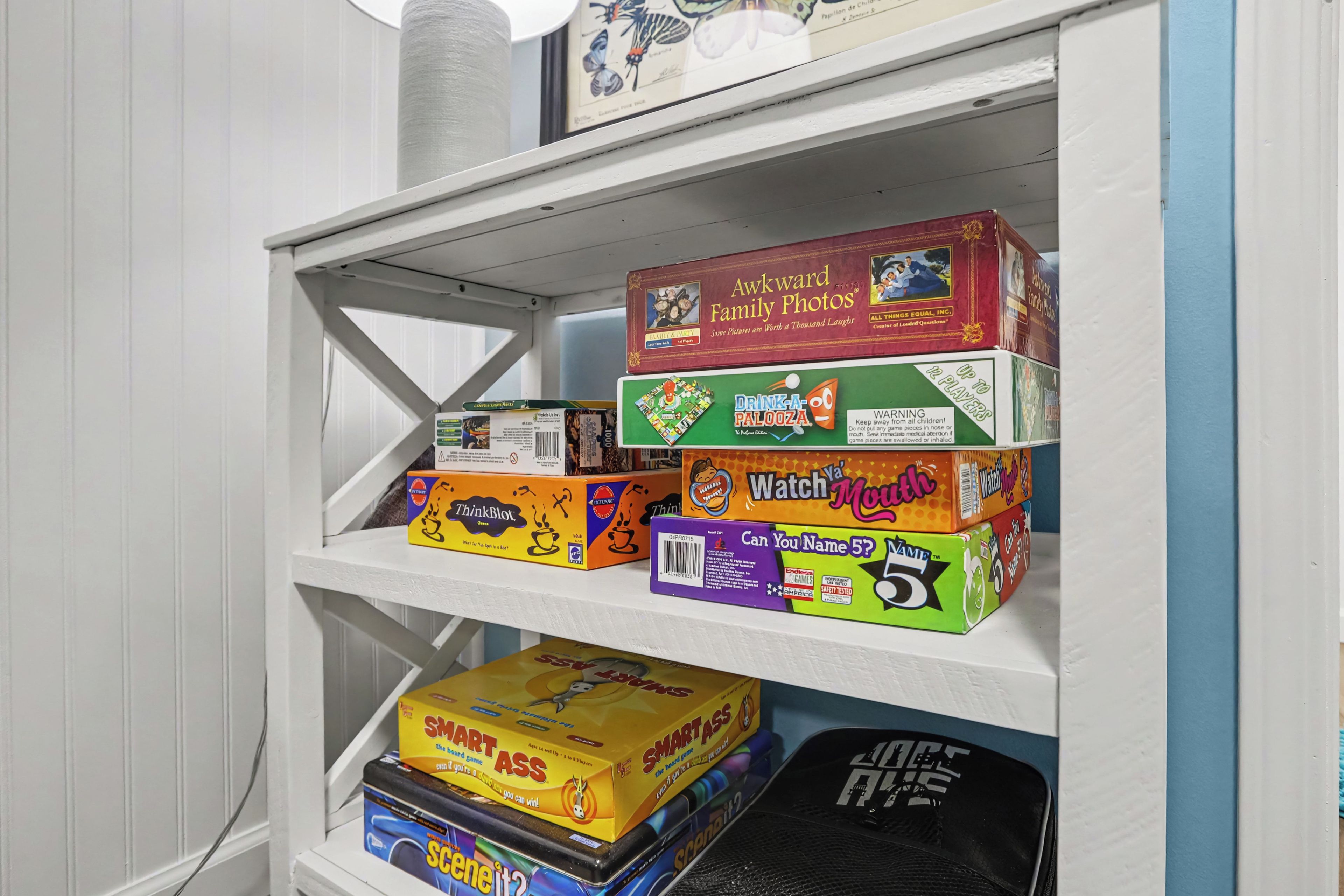 A shelf with various board games including 'Awkward Family Photos', 'Drink-a-Palooza', 'Watch Ya' Muth', 'Can You Name 5?', 'Smart Ass', and 'Scene it?'.