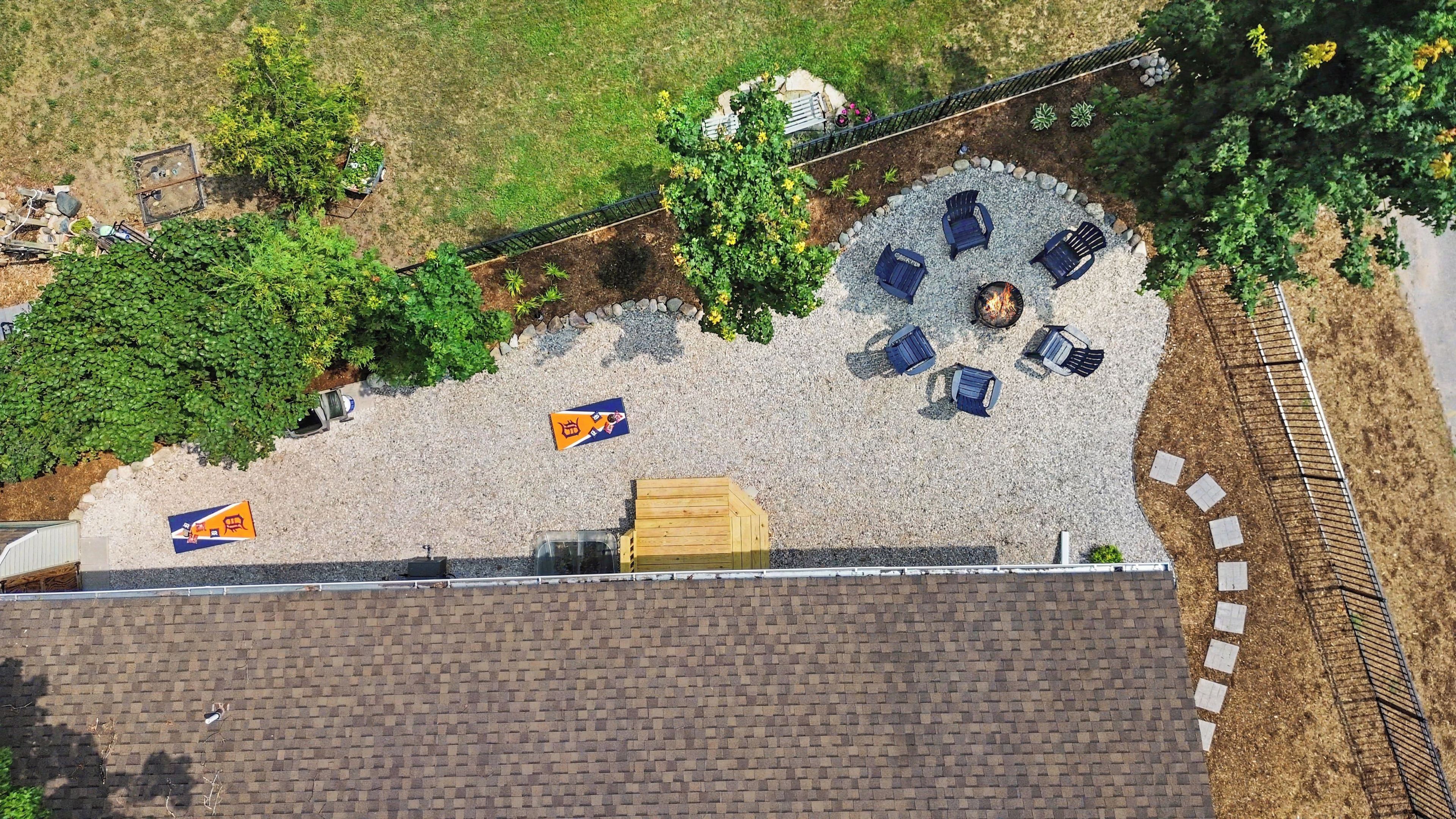 An aerial view of a courtyard with a fire pit, seating area, and surrounding vegetation.