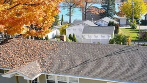 Ein eingeschossiges Gebäude mit Garage, überdachter Veranda und kleinem Vorgarten mit Baum.