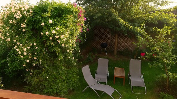 A garden with a wooden deck, two lounge chairs, a small table, and a grill. - Sudette 5 min from Paris with garden (Ivry-sur-Seine)