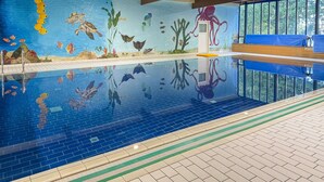 Piscina interna com mural da vida marinha, plataforma de mergulho e vista clara para o exterior.