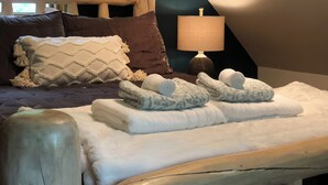 A bedroom with a bed, pillows, a lamp, and towels. - Oasis in the Blue Ridge Rt. 151 Brew Ridge Trail-Cozy Cottage in the mountains (Afton)
