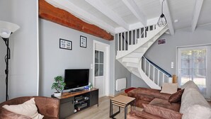 Ein Wohnzimmer mit Treppe, Fernseher und einer Pflanze.