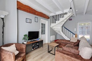 A living room with a staircase, a television, and a plant. - Gite Les Glycines – Near La Roche-Posay, Futuroscope, Beauval Zoo (Vicq-sur-Gartempe)