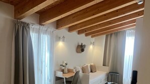 A bedroom with a bed, a desk, a chair, a sofa, and a small stool. - HOTEL LUNA NUEVA (Tarragona)