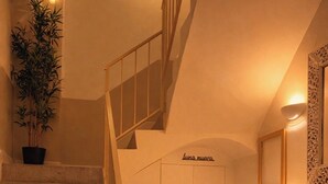 A staircase with a checkered floor, a wooden reception desk, and a potted plant. - HOTEL LUNA NUEVA (Tarragona)