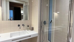 A modern bathroom with a glass-enclosed shower, a large mirror, and a white sink. - HOTEL LUNA NUEVA (Tarragona)