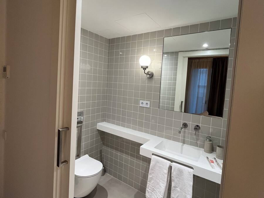A modern bathroom with a toilet, sink, and mirror.