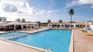 A swimming pool with a tiled deck, lounge chairs, and a palm tree. - Holiday Apartment 'Giuliana' with Shared Pool, Wi-Fi, and Air Conditioning (San Jaime Mediterráneo)