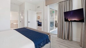Et moderne hotelværelse med seng, fjernsyn, skydedør og udsigt over det fri.
