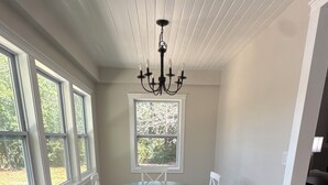 A room with a dining table, chairs, a chandelier, a patterned rug, and large windows. - Masters Week Rental-Spacious cottage in town! (Aiken)