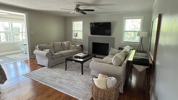 A living room with a fireplace, two sofas, a coffee table, and a ceiling fan. - Masters Week Rental-Spacious cottage in town! (Aiken)