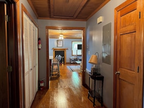 A hallway with wooden floors, a fire extinguisher, a lamp, and a door.