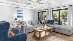 A modern living room with a sectional sofa, a round coffee table, and a ceiling fan. - Palmetto Dunes Villa – Golf, Pools & Bike to Beach (Hilton Head Island)