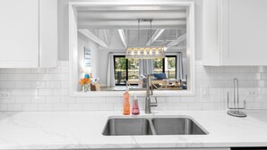A modern kitchen with a large window, white cabinetry, and a stainless steel sink. - Palmetto Dunes Villa – Golf, Pools & Bike to Beach (Hilton Head Island)