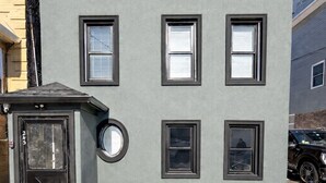 A modern building with multiple windows, a black door, and a small circular window. - Fully Renovated 2BR Executive Residence Near NYC (Cliffside Park)