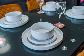 Een gedekte tafel met witte kommen en borden, een wijnglas en een glas water.