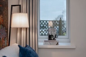 A room with a window, a lamp, and a stack of books on the windowsill.