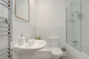 A modern bathroom with a glass-enclosed shower, a white sink, and a toilet.