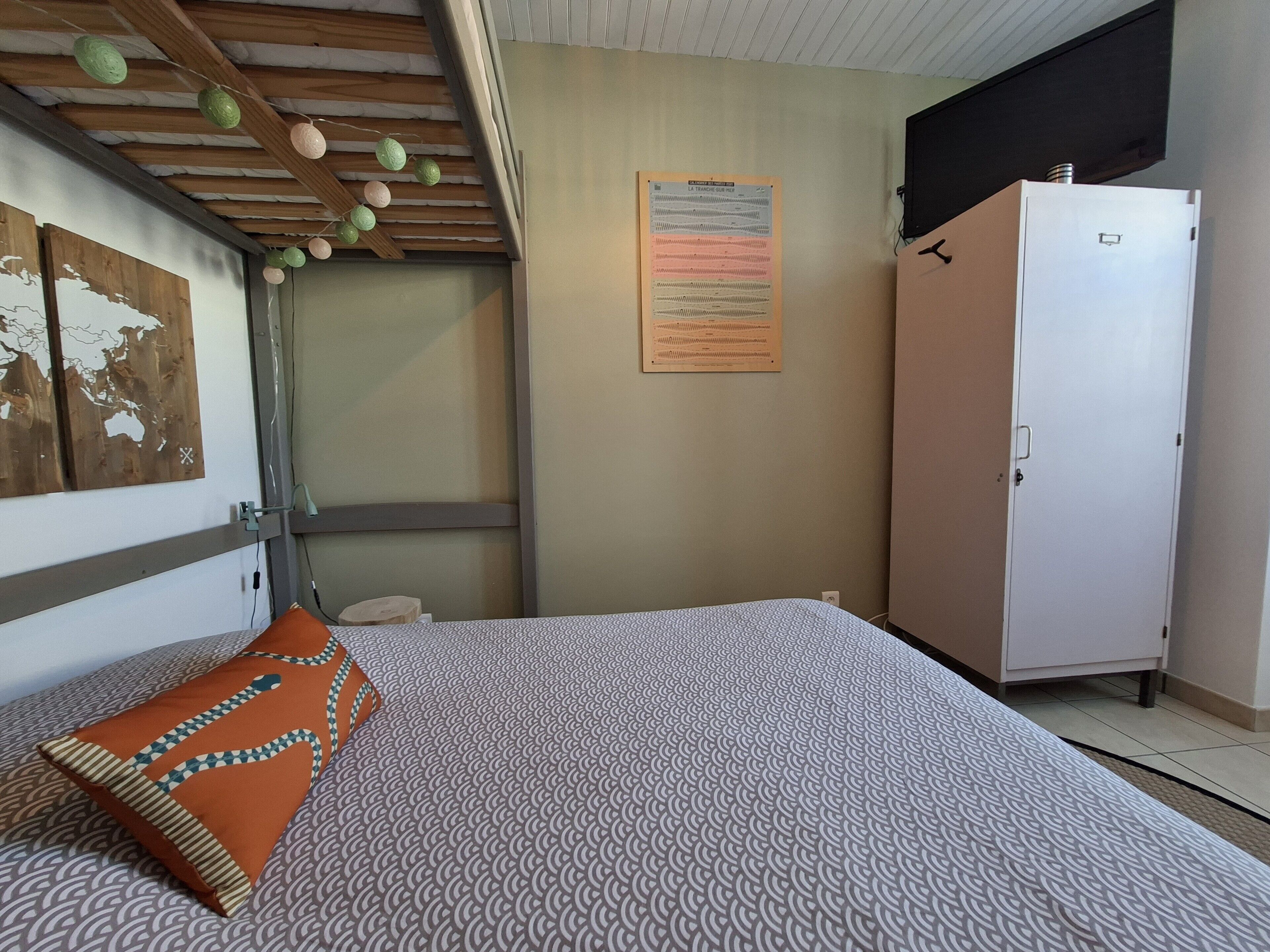 A bedroom with a bed, a wardrobe, a map on the wall, and a bulletin board.