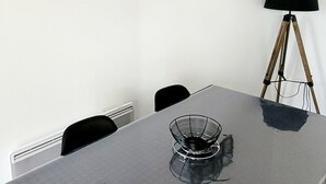 Una mesa de comedor con sillas, un cuadro enmarcado, una lámpara y un radiador.