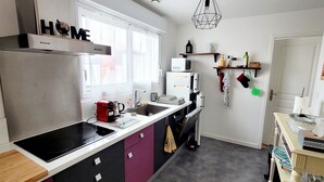 Cocina compacta con refrigerador, microondas y estufa, un lavamanos pequeño y una ventana con vista.