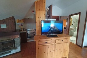 Una cocina con un mueble de madera, un televisor encima y un salpicadero de azulejos.