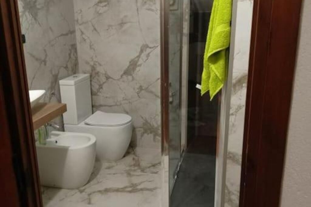 Un baño con inodoro, bidé y cabina de ducha de cristal.