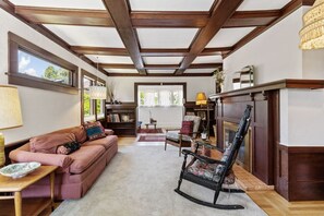A living room with a fireplace, a rocking chair, a sofa, and a bookshelf.