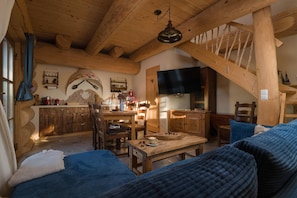 A rustic cabin interior with wooden furniture, a dining area, and a television. - Two-level Apartment With a Large Terrace (gmina Będzino)