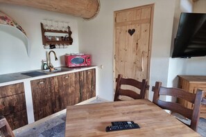 A compact kitchen with a wooden cabinet, a microwave, a sink with a faucet, and a television mounted on the wall. - Two-level Apartment With a Large Terrace (gmina Będzino)