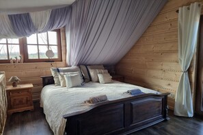 A bedroom with a sloped ceiling, a bed with multiple pillows, a bedside table with a lamp, and a window with curtains. - Two-level Apartment With a Large Terrace (gmina Będzino)