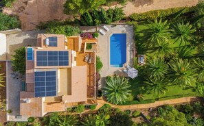 Een woonhuis met een zwembad, zonnepanelen en een verzorgde tuin.