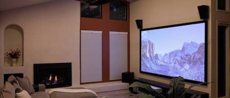 Un salon doté d’une cheminée, d’un grand téléviseur à écran plat et d’un ventilateur de plafond.