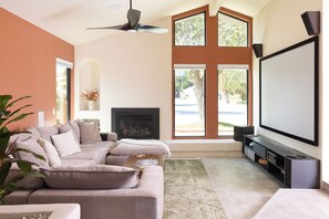 Una sala de estar con sofá, chimenea, televisor y ventanas amplias.