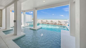 A pool area with clear blue water, white pillars, and a view of the beach. - Beachfront Luxury - Pool, Spa & Rooftop Deck (Clearwater)