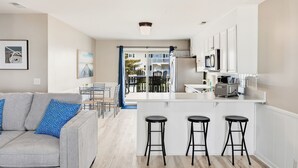 Una cocina moderna con una isla central, taburetes de bar y un comedor con sillas.