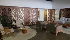 A modern living room with a sectional sofa, armchairs, a coffee table, and decorative wooden panels. - Ora Beach poucos passos do mar by LP (Ipojuca)